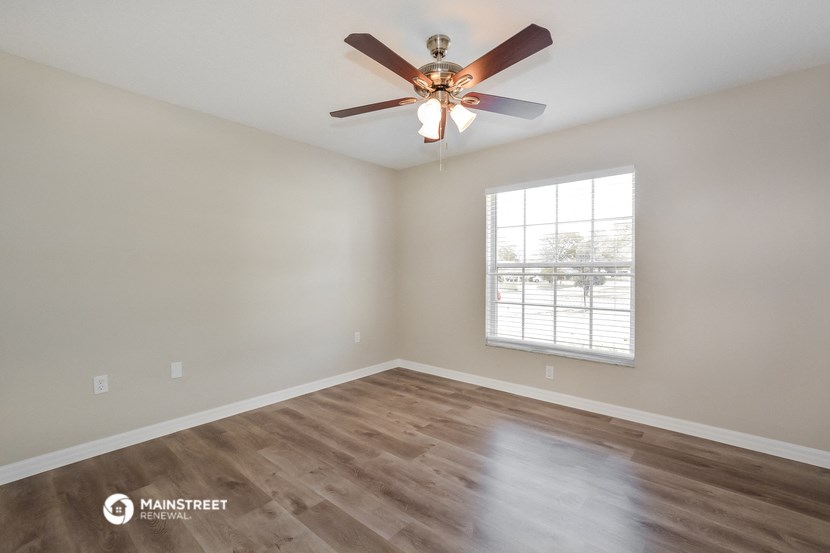 the spacious living room with a ceiling fan and a window
