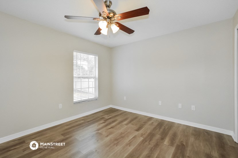 the spacious living room with ceiling fan and wood flooring
