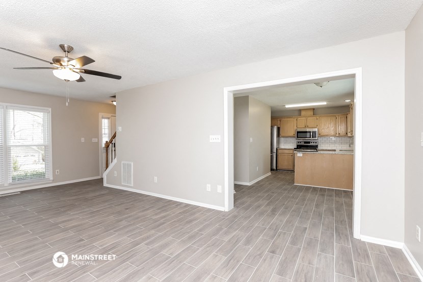 the living room and kitchen of an empty house with a ceiling fan