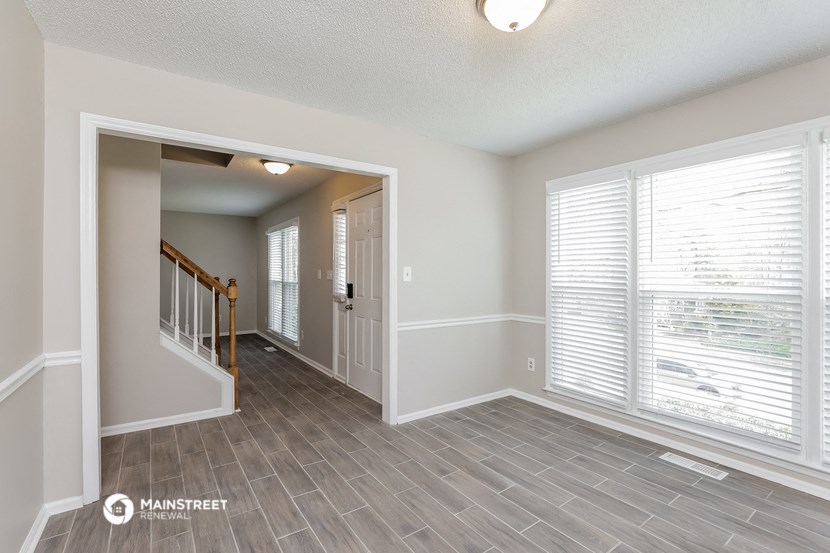 the living room and dining room with a large window and wood flooring