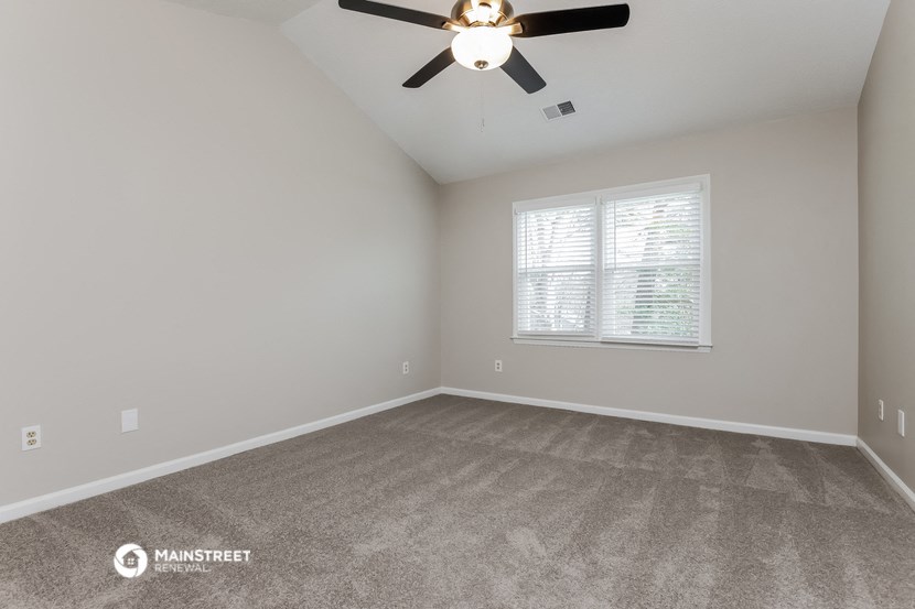 the spacious living room with carpeting and a ceiling fan