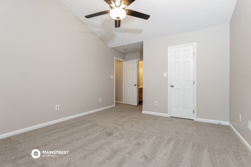 the spacious living room with carpet and a ceiling fan