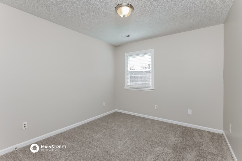the spacious living room with carpeting and a window
