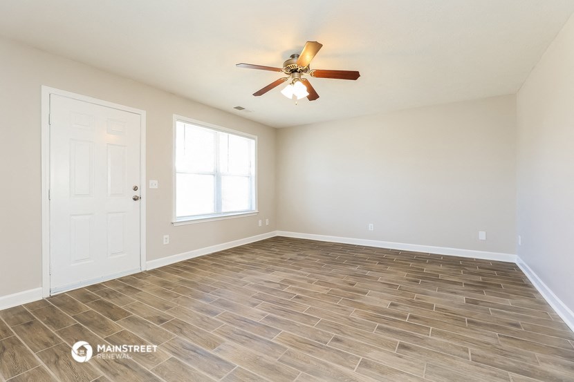 the spacious living room with vinyl flooring and a ceiling fan