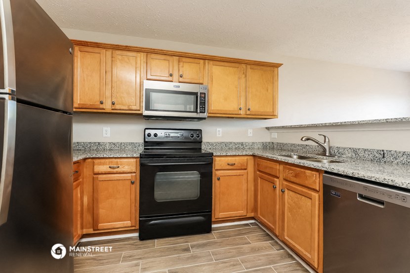 a kitchen with black appliances and wooden cabinets and granite counter tops