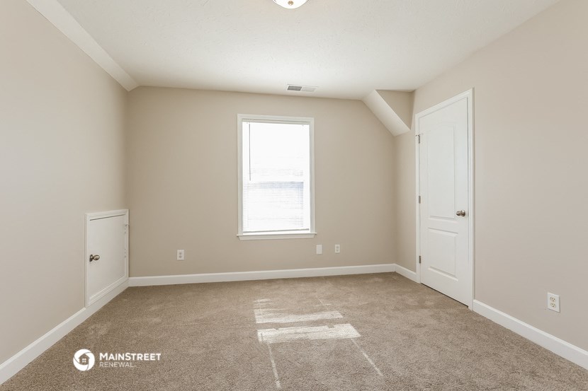 the spacious living room with carpeted flooring and a window