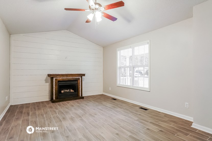 the living room with wood floors and a fireplace