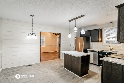 a kitchen with white walls and black cabinets and a white counter top