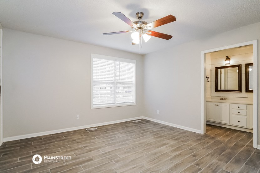 the spacious living room with wood floors and a ceiling fan