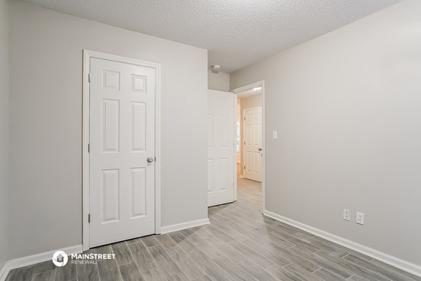 the living room of an apartment with a door and a hallway to the bedroom