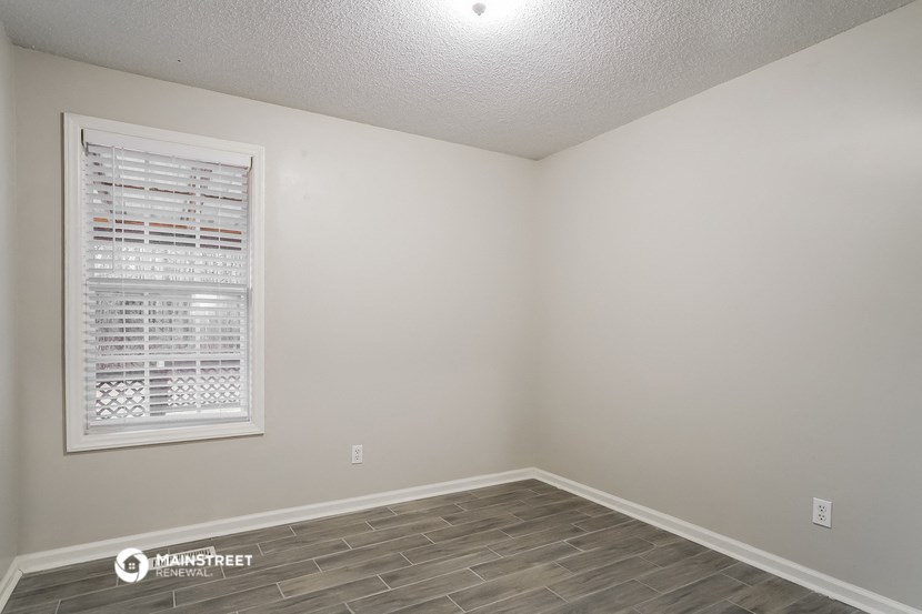 the living room of an apartment with a window and wood flooring