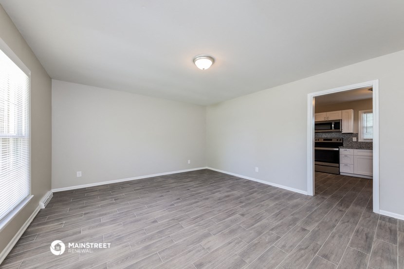 the spacious living room with wood flooring and a kitchen