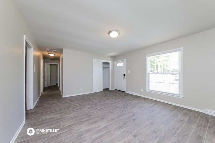 the living room is spacious and has a large window and hardwood flooring