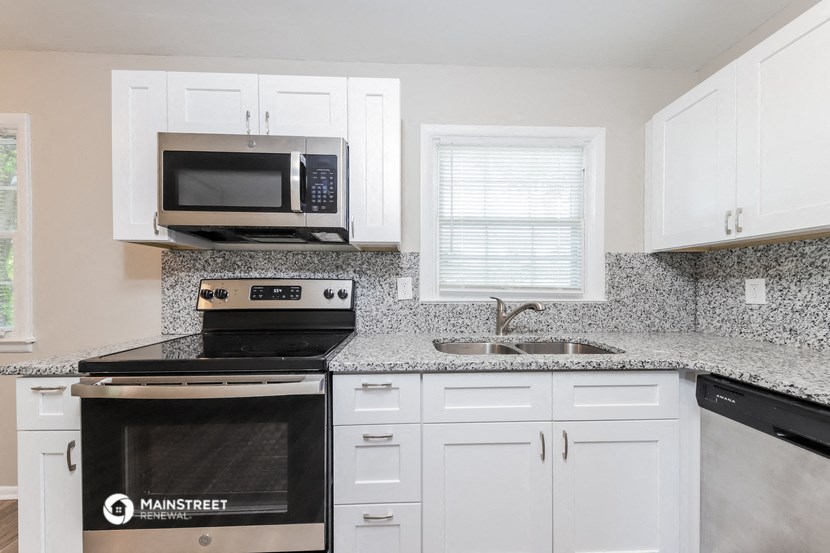 a kitchen with white cabinets and a black stove and a microwave
