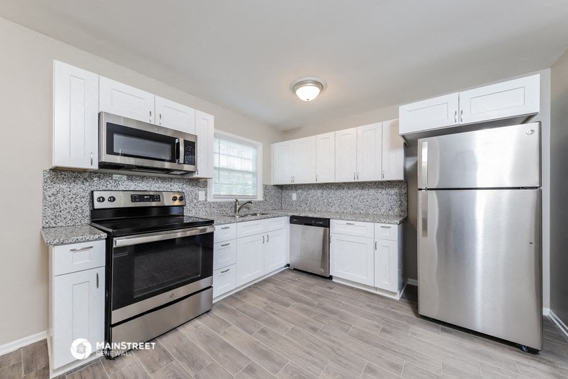 an empty kitchen with stainless steel appliances and white cabinets