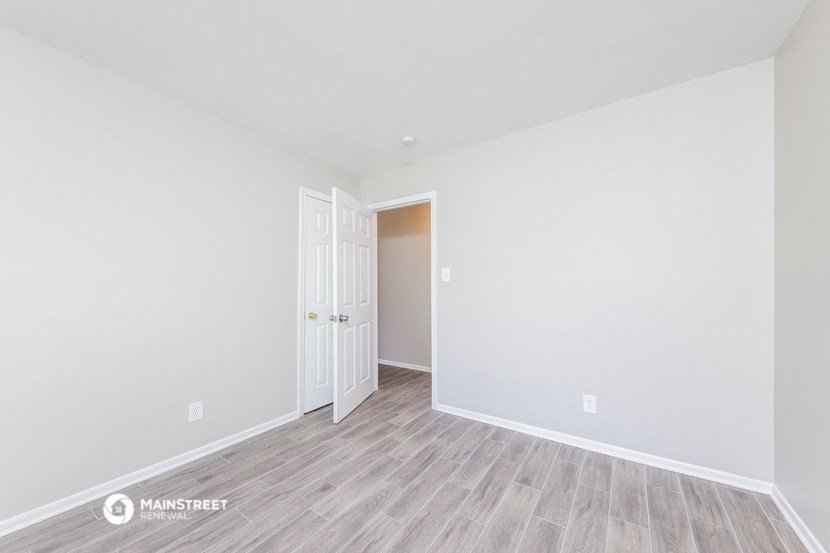the living room of an apartment with white walls and wood floors