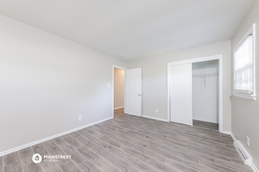 the spacious living room with white walls and wood flooring