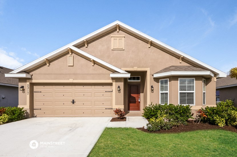 a tan house with a garage door and a driveway