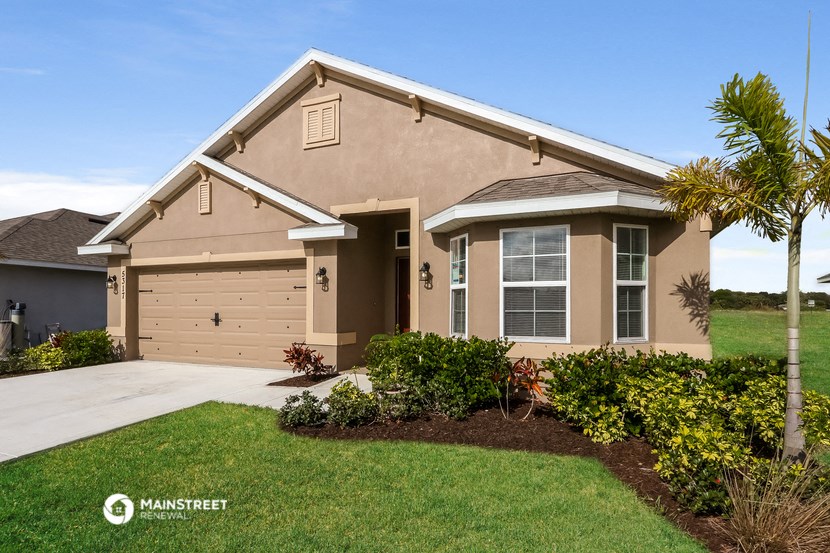 a beige house with a garage and a lawn