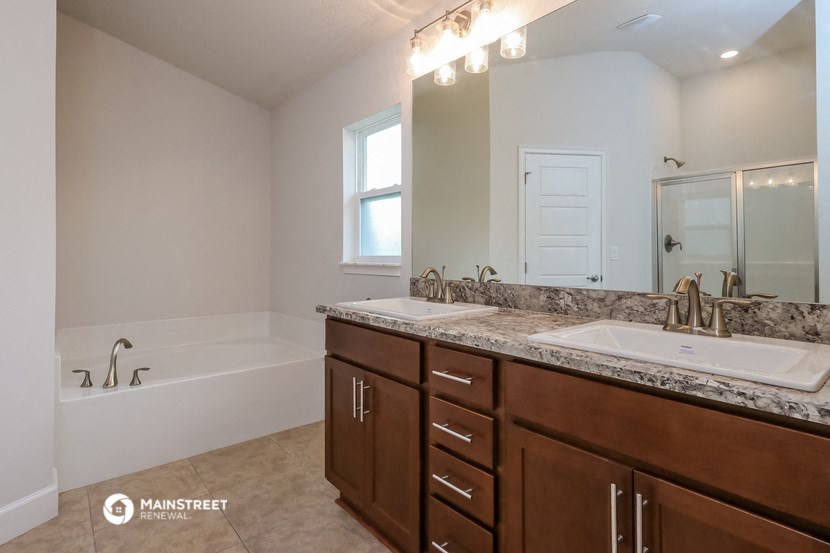 a bathroom with two sinks and a tub and a mirror