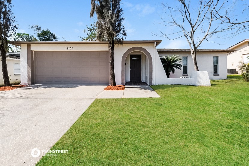 a white house with a garage door and a lawn