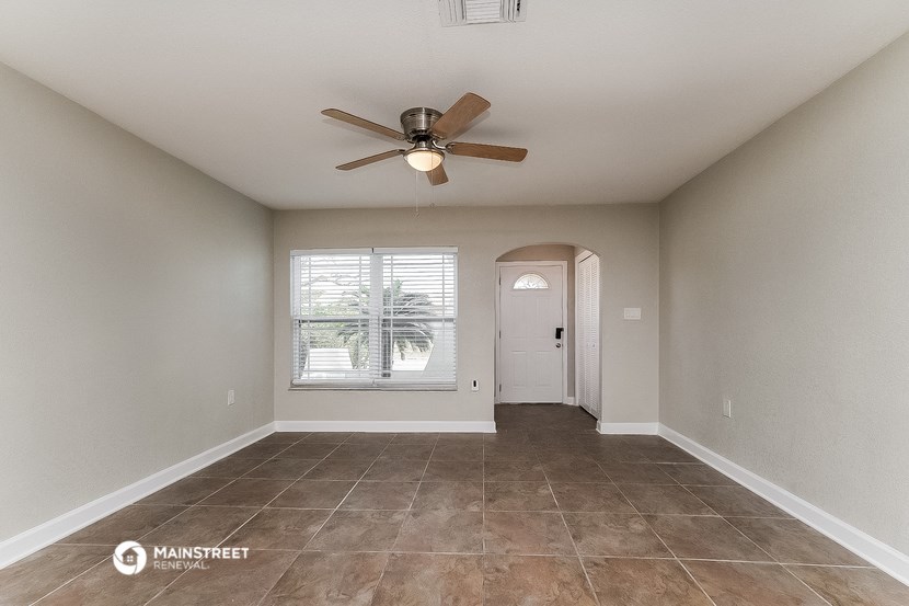 the spacious living room with ceiling fan and tile flooring