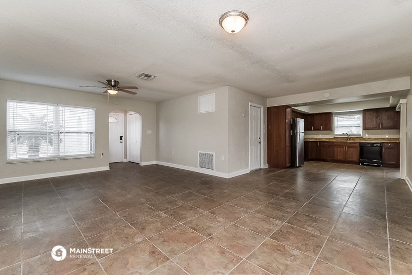 an empty kitchen and living room with tile flooring and a ceiling fan