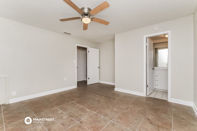 the spacious living room with tile flooring and a ceiling fan