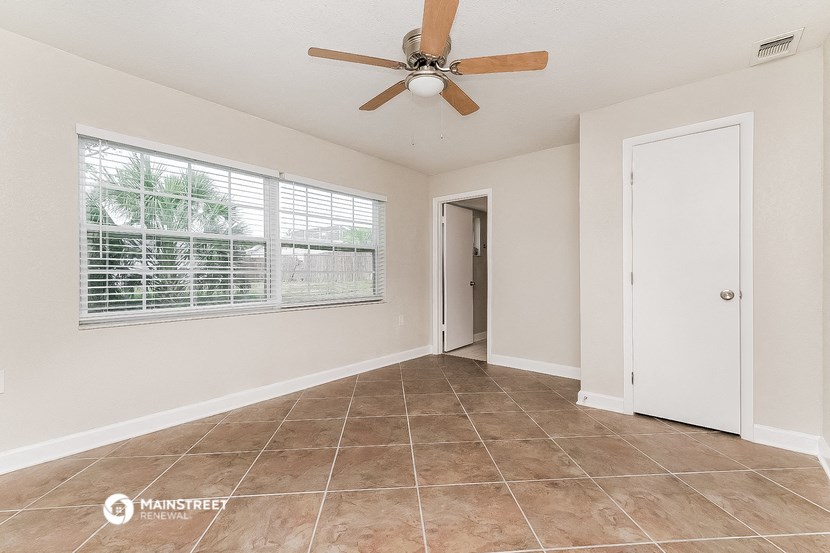the living room of a home with a large window and a ceiling fan