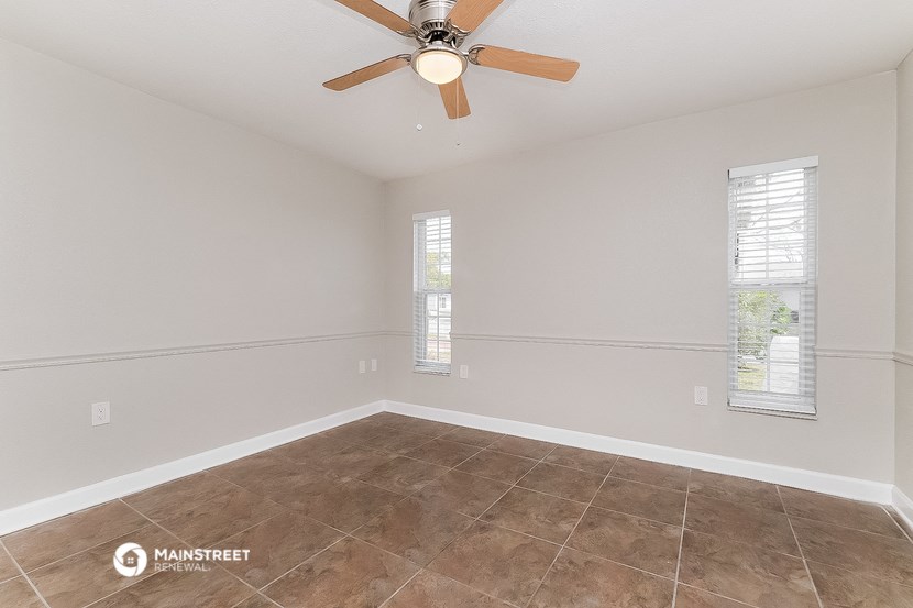 the spacious living room with a ceiling fan and tile flooring