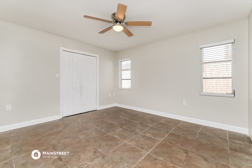 the spacious living room with a ceiling fan and tile flooring