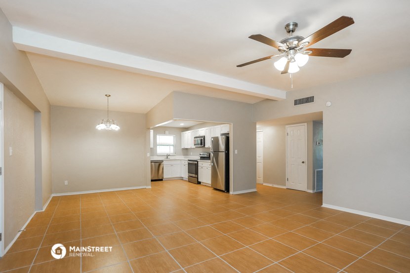 a living room with a ceiling fan and a kitchen