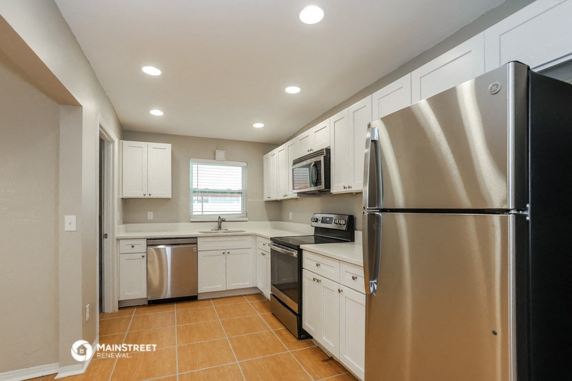 an updated kitchen with stainless steel appliances and white cabinets