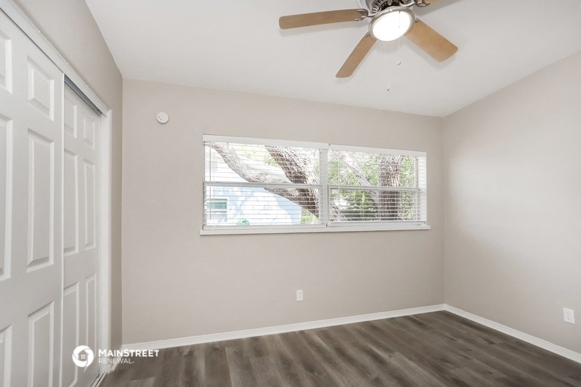 an empty bedroom with a large window and a ceiling fan