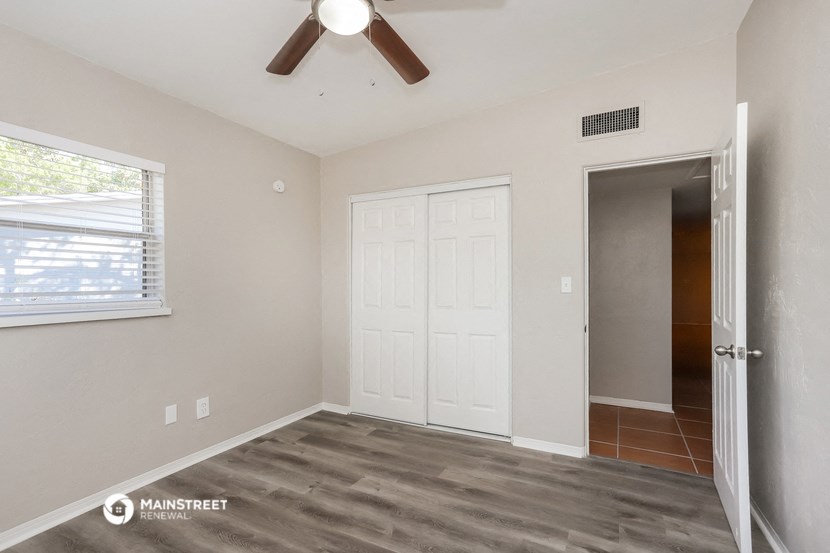 a bedroom with a ceiling fan and a door to a closet