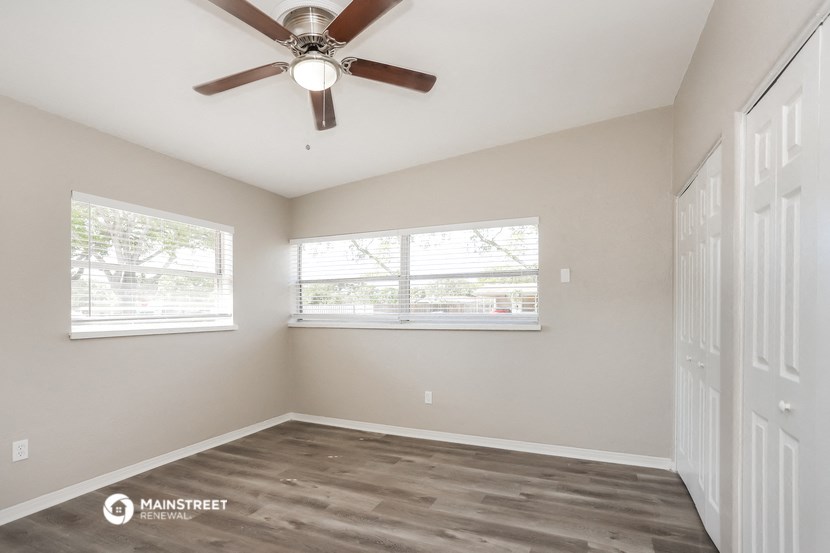 an empty bedroom with a ceiling fan and two windows
