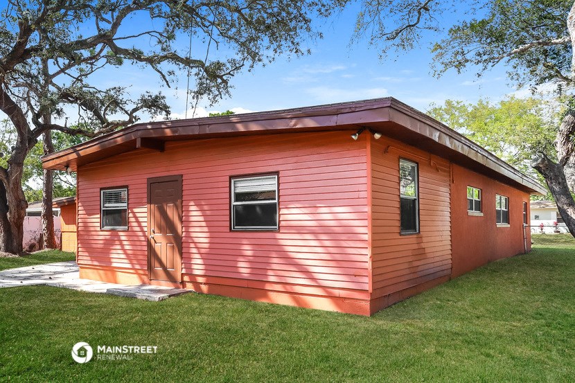 a small red house with a tin roof on a lawn