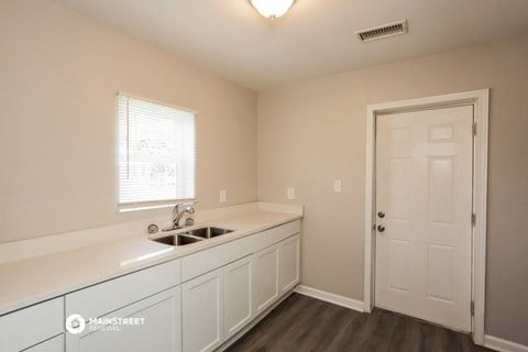 a kitchen with white cabinets and a sink and a door