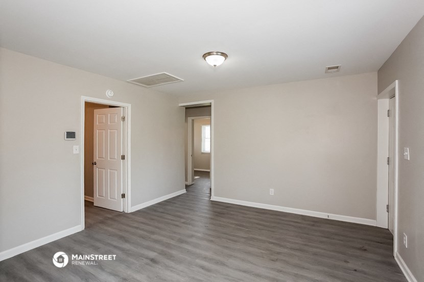 the spacious living room with white walls and wood flooring