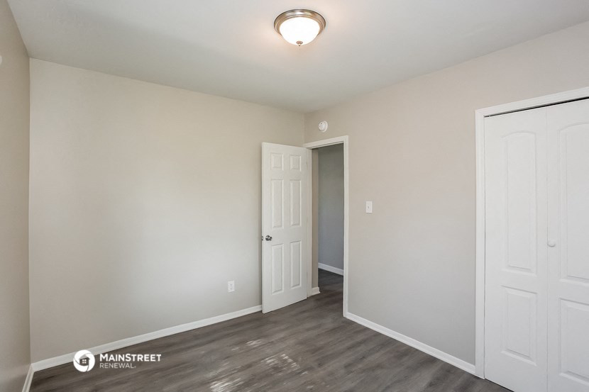 the spacious living room with white walls and wood flooring