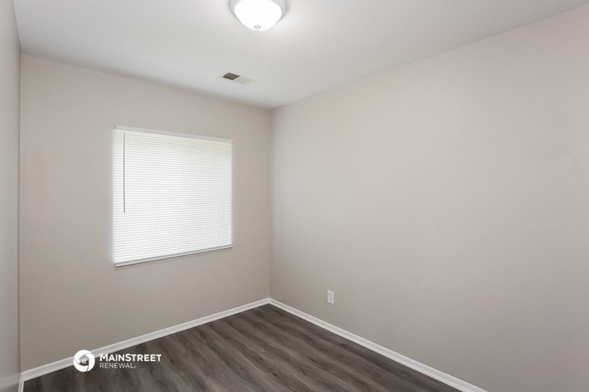 the interior of an empty room with wood flooring and a window