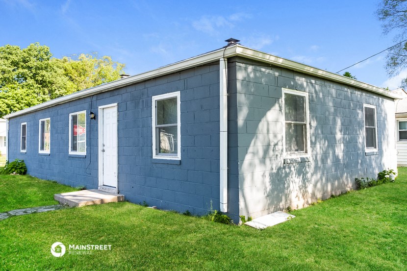 a blue house with white doors and windows on a lawn