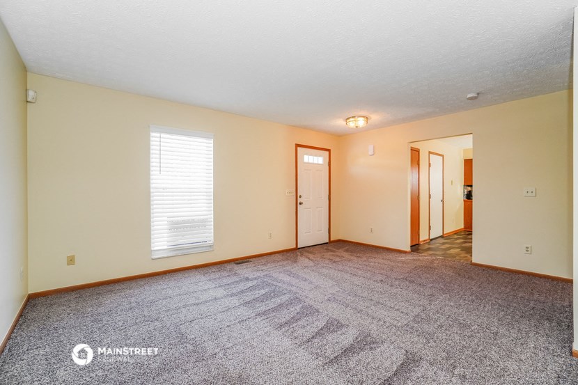 the living room of an empty house with a carpeted floor and a door to