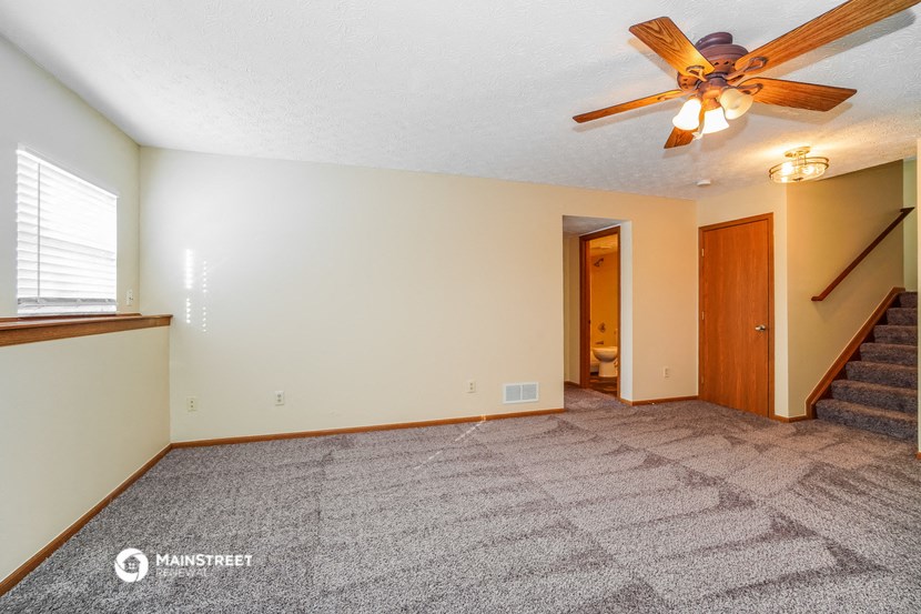 the living room with carpet and a ceiling fan