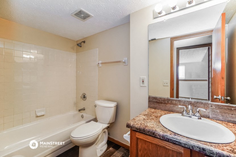 a bathroom with a toilet sink and tub and a mirror