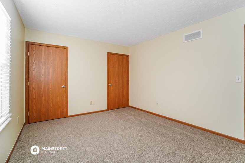 a bedroom with carpet and a door to a closet