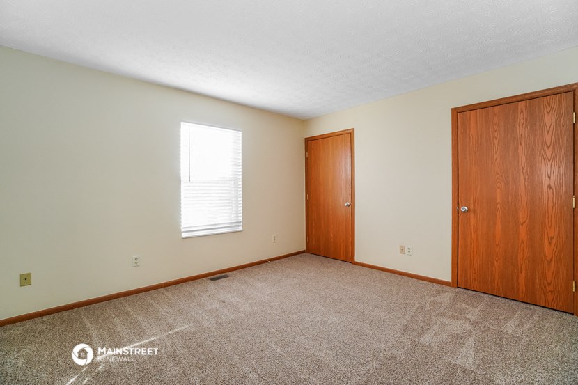 the master bedroom of this home has carpeting and a door to the bathroom