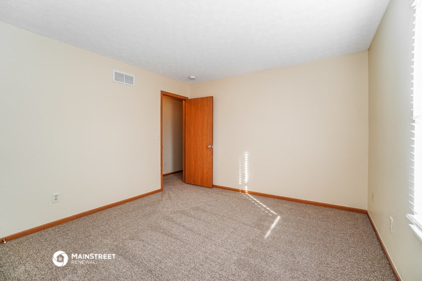 a bedroom with carpet and a door to a closet