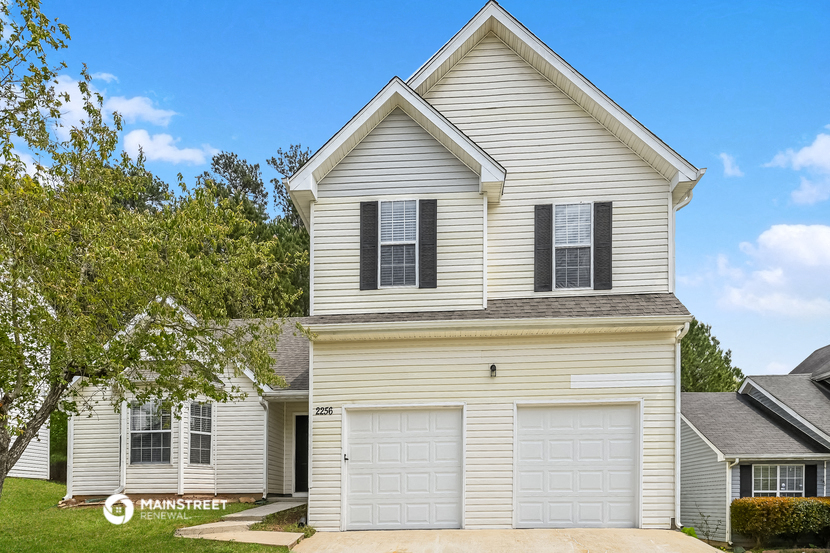a white house with two garage doors and a lawn