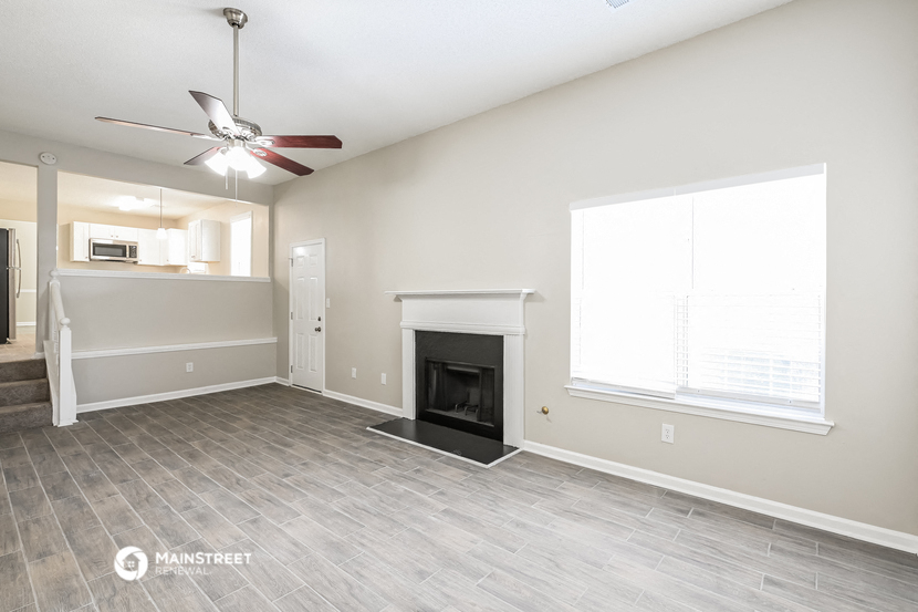 a living room with a fireplace and a ceiling fan